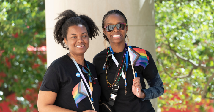 Two team members smile with rainbow flags.
