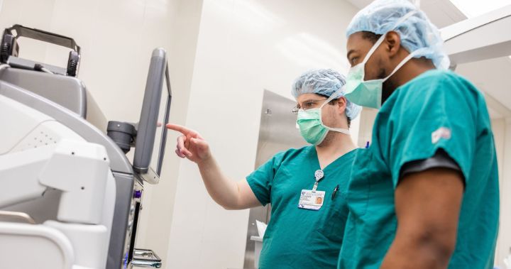 Two male team members work with equipment in the OR.