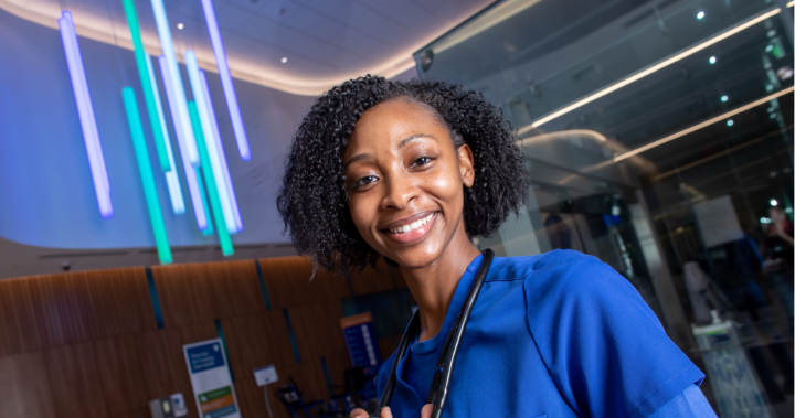 nurse jaysia brown smiling in front of multicolored lights in the duke raleigh hospital entrance
