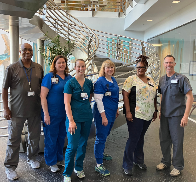 Six Duke HomeCare & Hospice team members smile together.