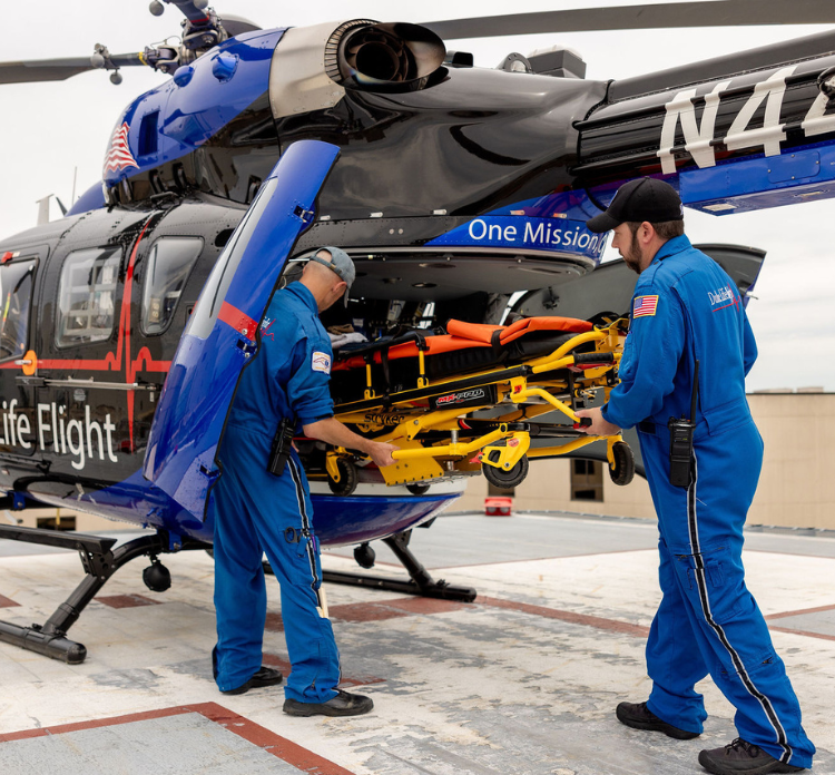 two team members unload patient from life flight helicopter.