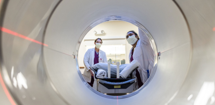 Two team members look inside imaging machine.