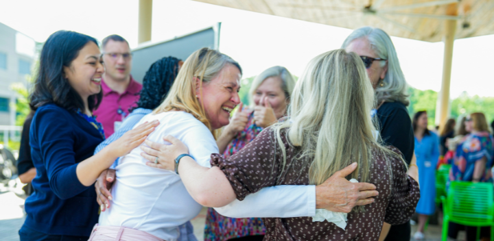 Group of team members laugh together in casual setting.