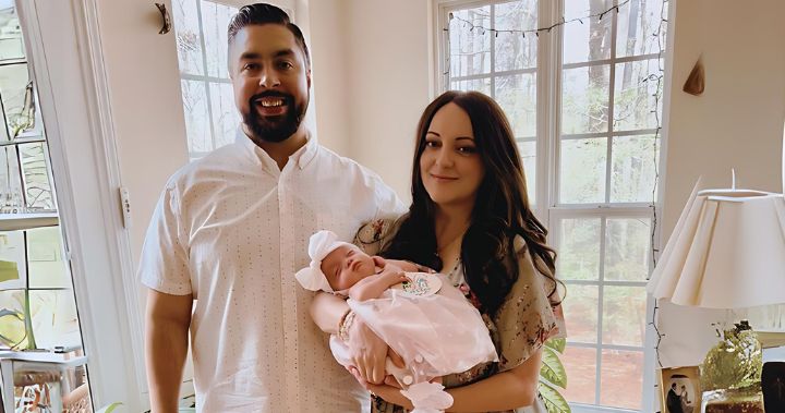 Jessica and her husband smiles while holding her newborn daughter.