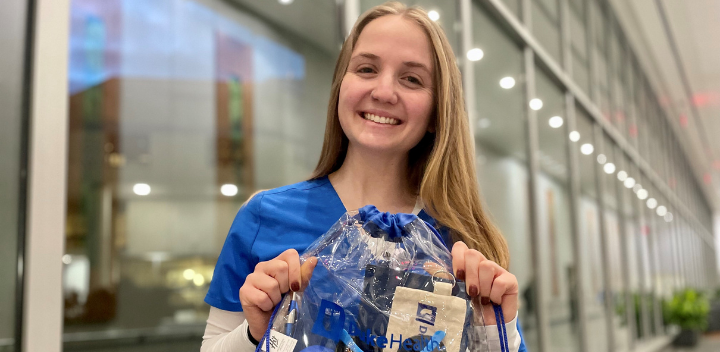 Lindsay smiles in blue scrubs in the hospital with a bag of prizes.