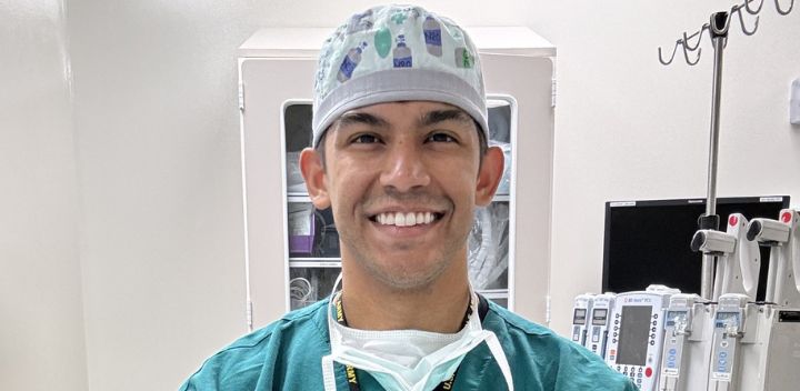 Kevin smiles in scrubs and a scrub hat.