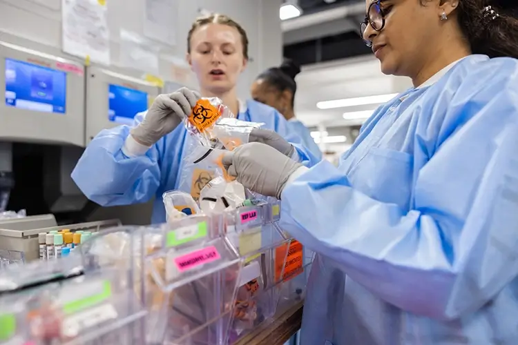 2 female employees in lab coats handling bio samples in a lab setting