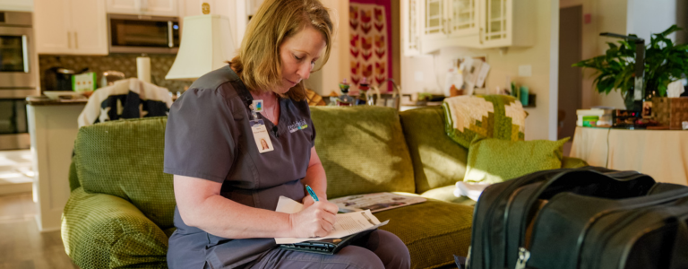 A nurse taking notes while sitting on the couch.