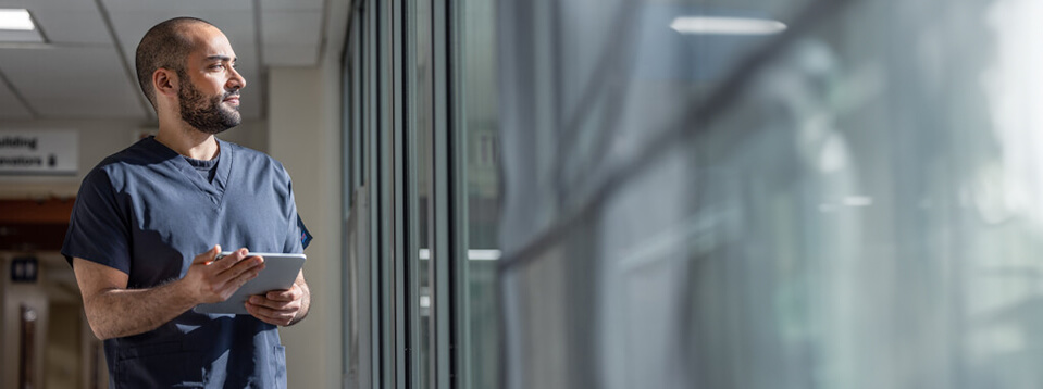 Employee holding a tablet while gazing through a window.