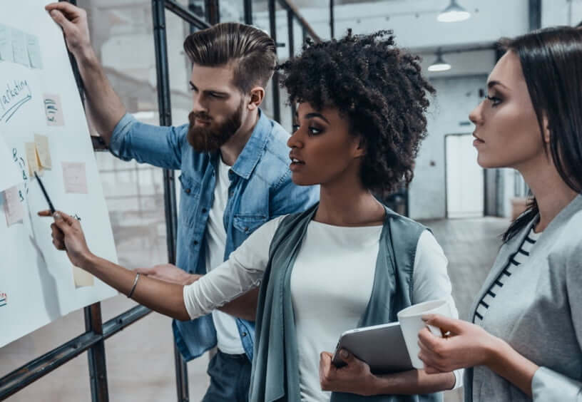 two women and a man at whiteboard