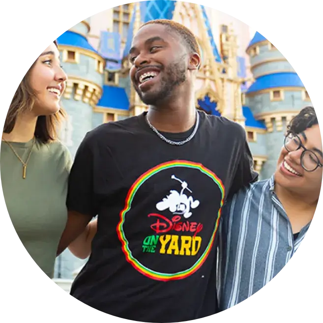3 young people smiling and linking arms in front of a Disney castle