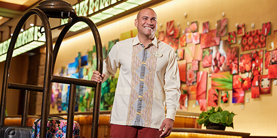 Man moving luggage on a rack, through a hotel lobby.