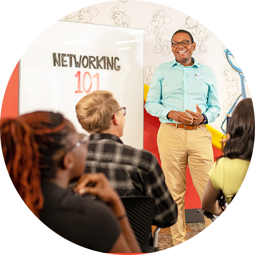 A teacher standing in front of a poster that reads 'networking 101'