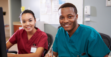 portrait of two nurses at station desk