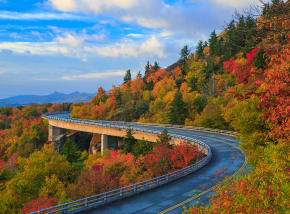 Linn Cove Viaduct on the Blue Ridge parkway in the fall season. Road winding through the mountains with autumn colors and blue vibrant morning skies.