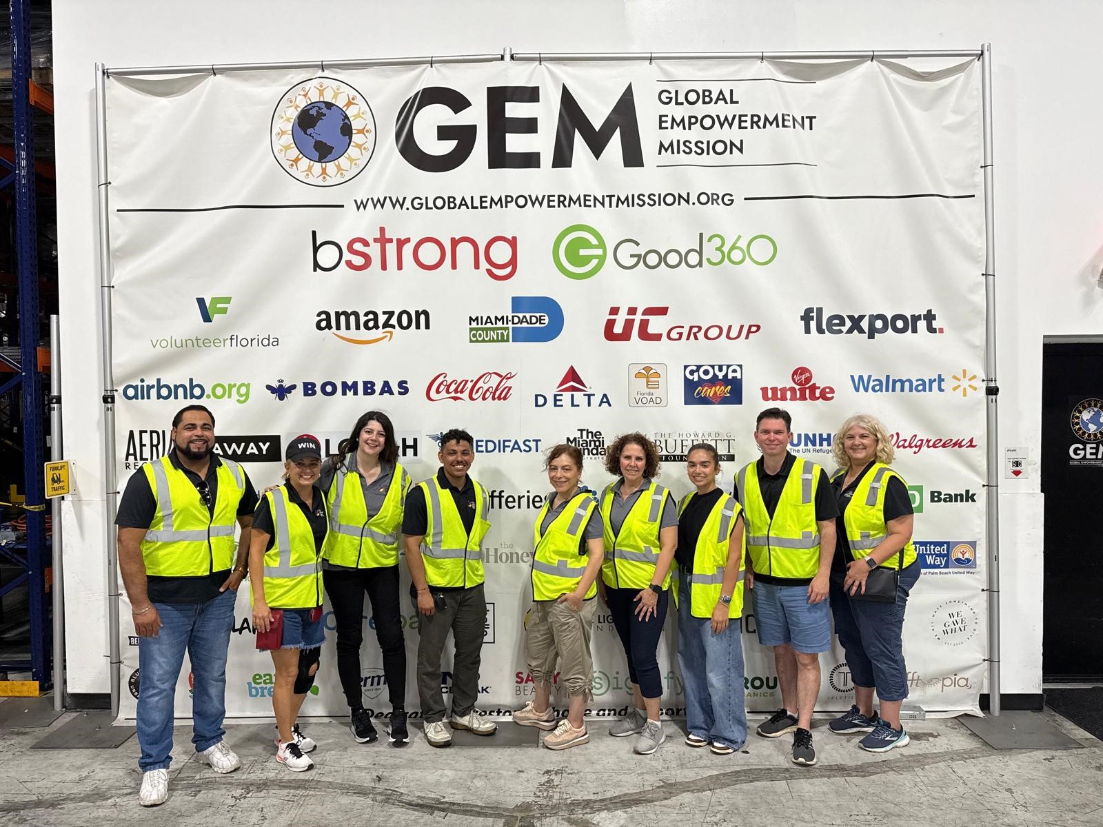 Volunteer team posing in neon vests at an event banner