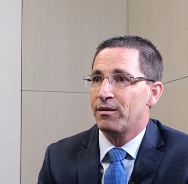 Man in a suit and tie speaking during an interview