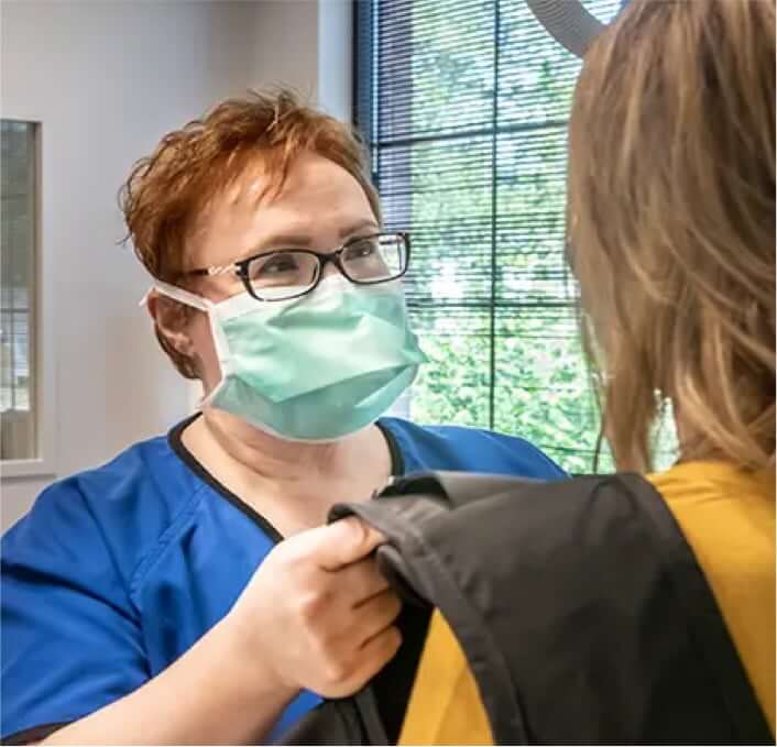 Female imaging specialist helping patient put on imaging jacket