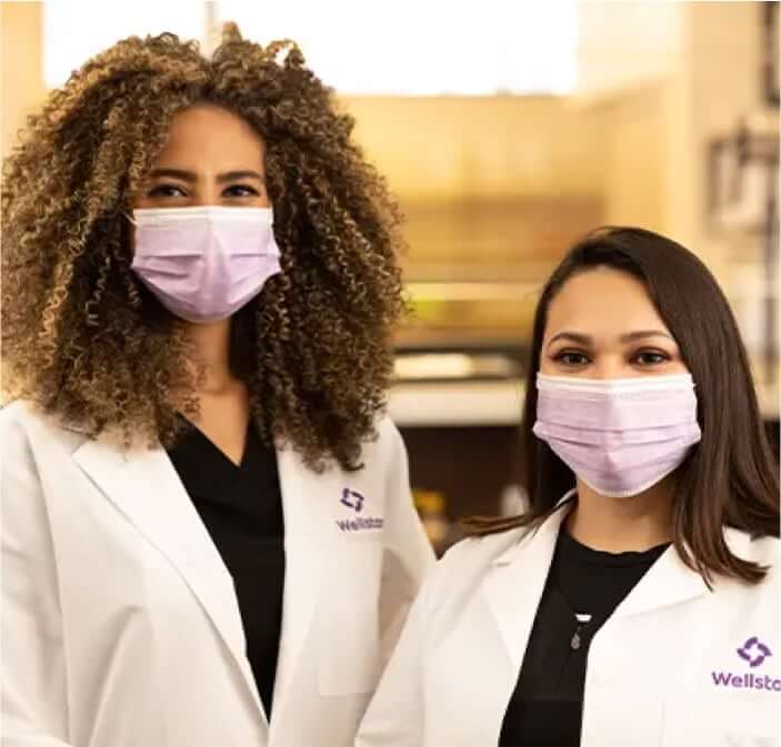 Two female pharamcists posing for a picture wearing medical masks