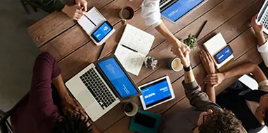 People sitting around a table working and on their laptops