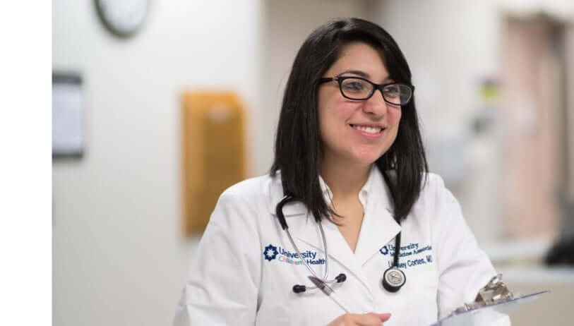 Female doctor smiling while writing on a notepad