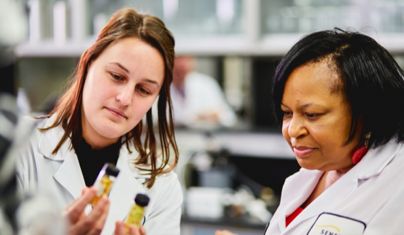 2 people in lab coats looking at a sample in a lab