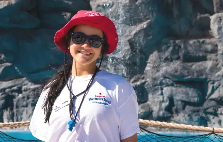 Female lifeguard smiling for a picture in front of an aquatics pool