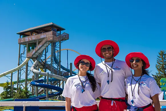 three lifeguards standing in front of a water slide