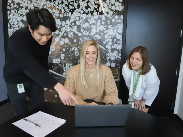 three iRobot employees viewing a laptop