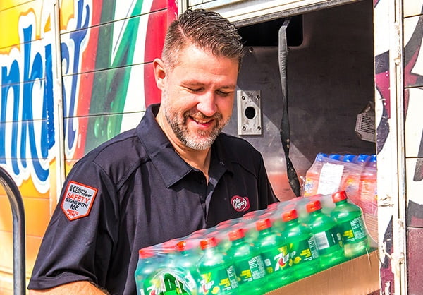 Male employee carrying a case of Seven Up