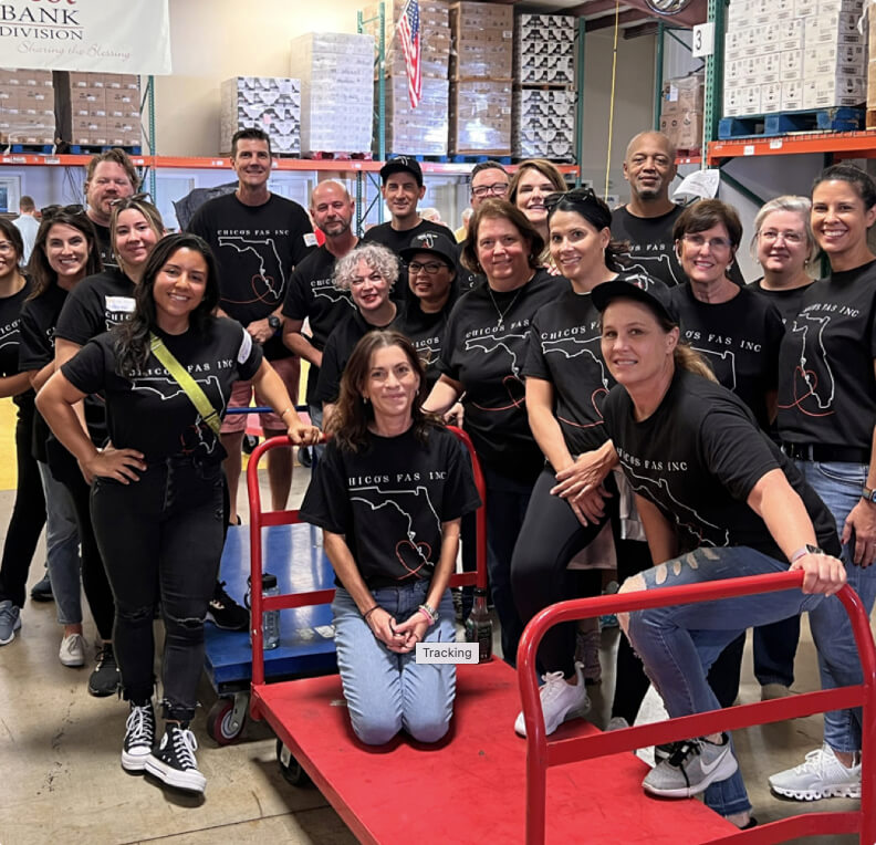 Group of Chicos employees in matching shirts in a warehouse