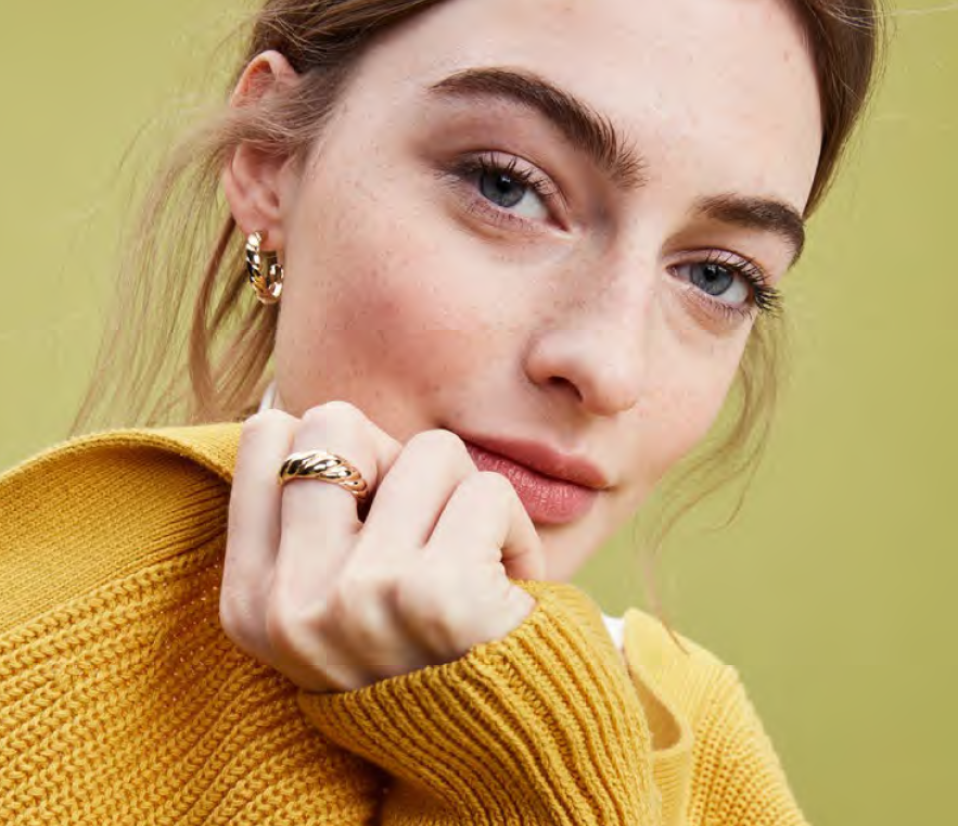 Model in a yellow sweater and gold ring.