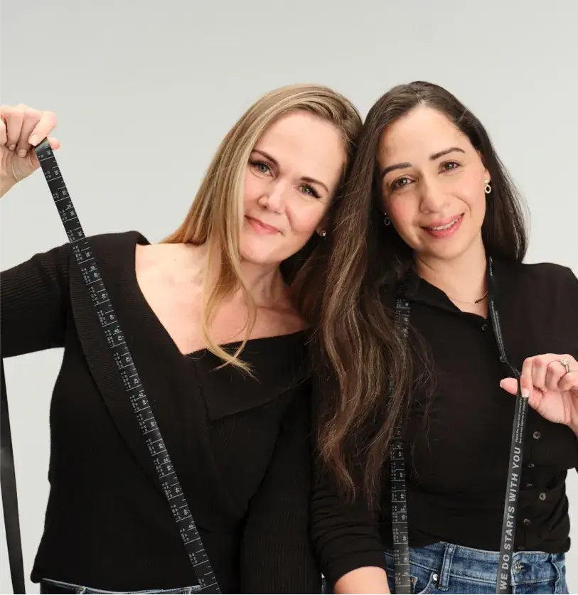 Two women holding black measuring tape