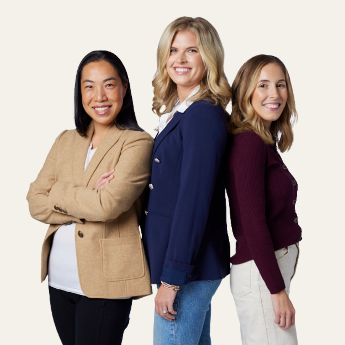 Three women in blazers standing back-to-back.