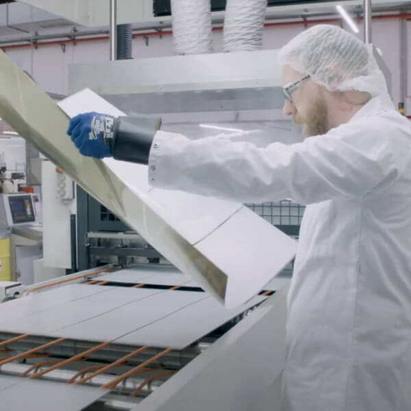 Man in white clothes wearing gloves looking at materials