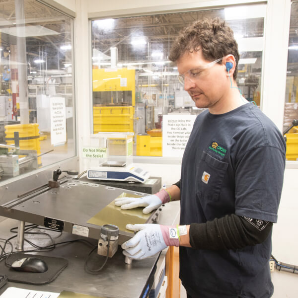 Man wearing gloves and protective eyewear operating a machine