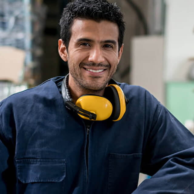 Man in overalls and with protective equipment smiling
