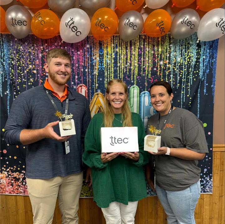 Three TTEC team members celebrating with recognition awards.