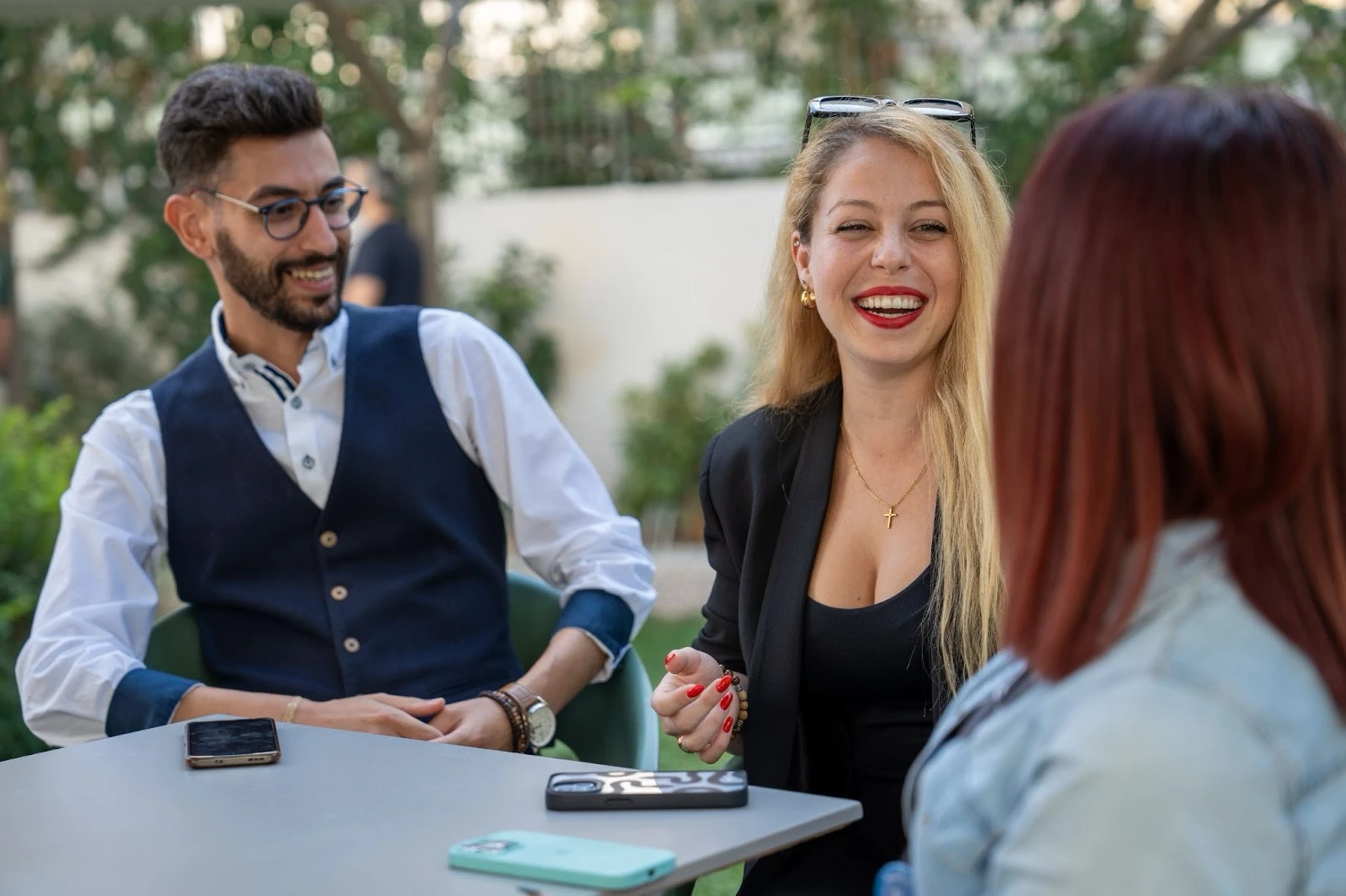 Three TTEC colleagues having a discussion at a table outdoors.