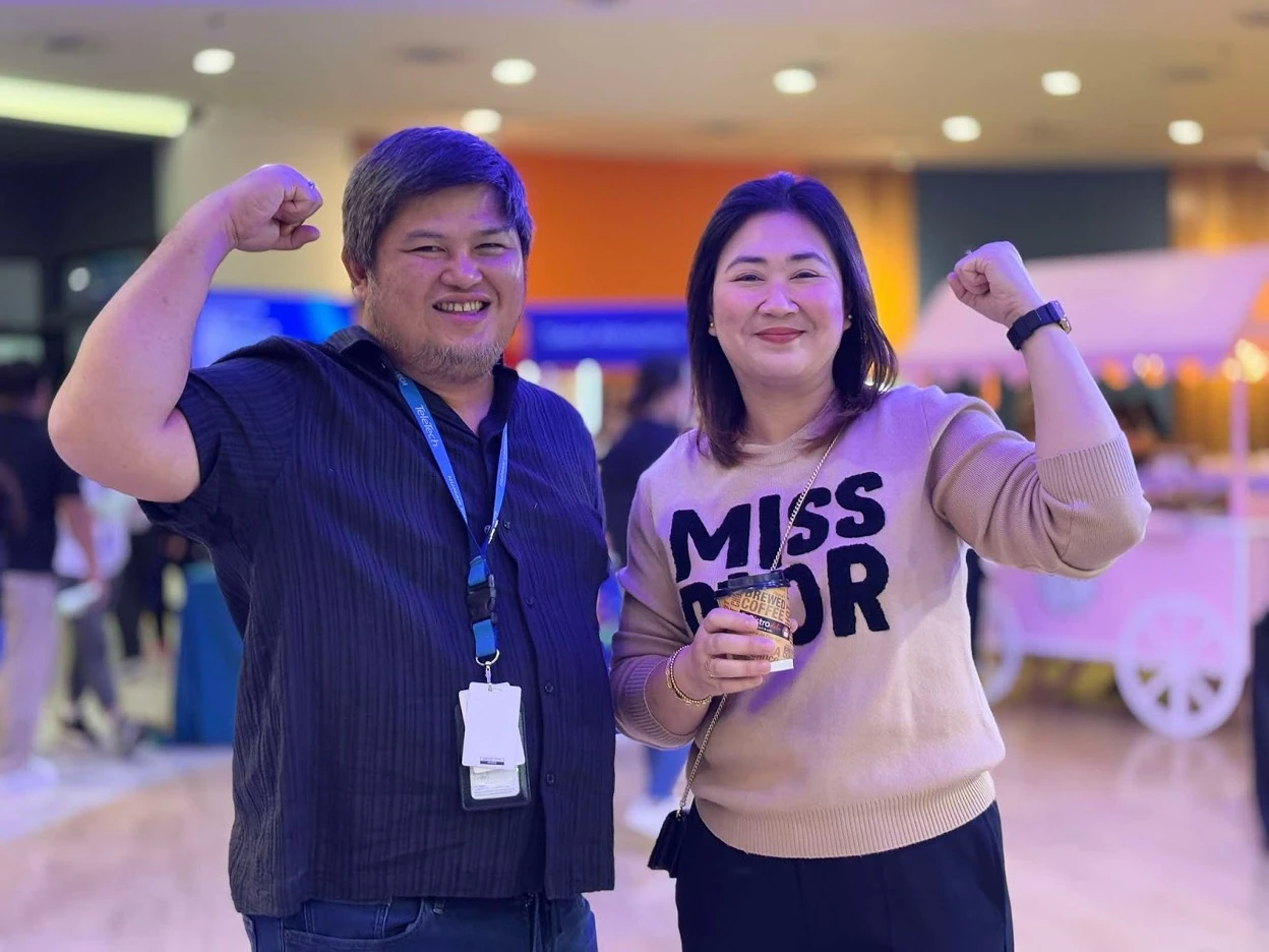 Two TTEC employees flexing their arms in a celebratory pose.