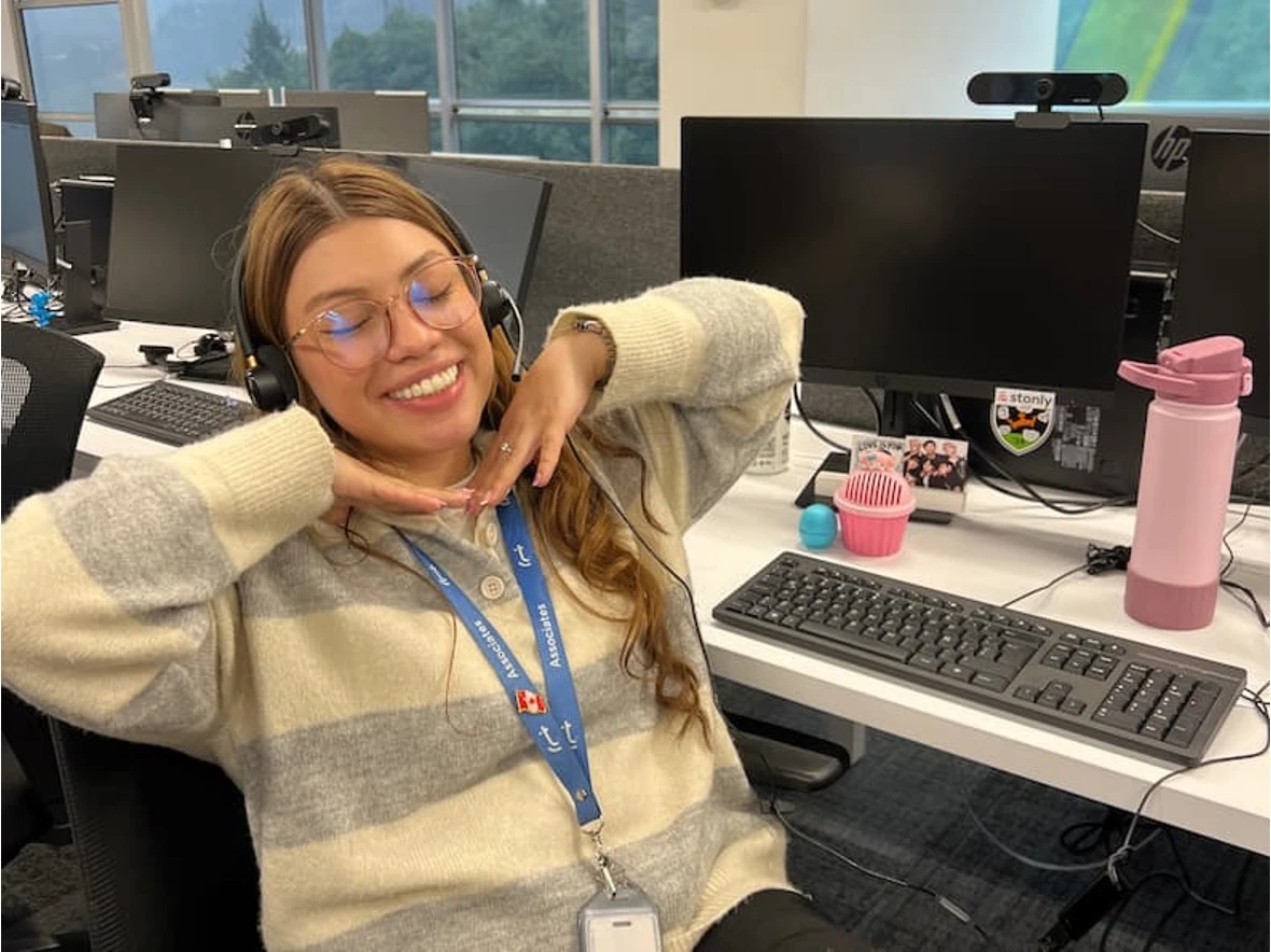 TTEC employee smiling while wearing a headset at her desk.