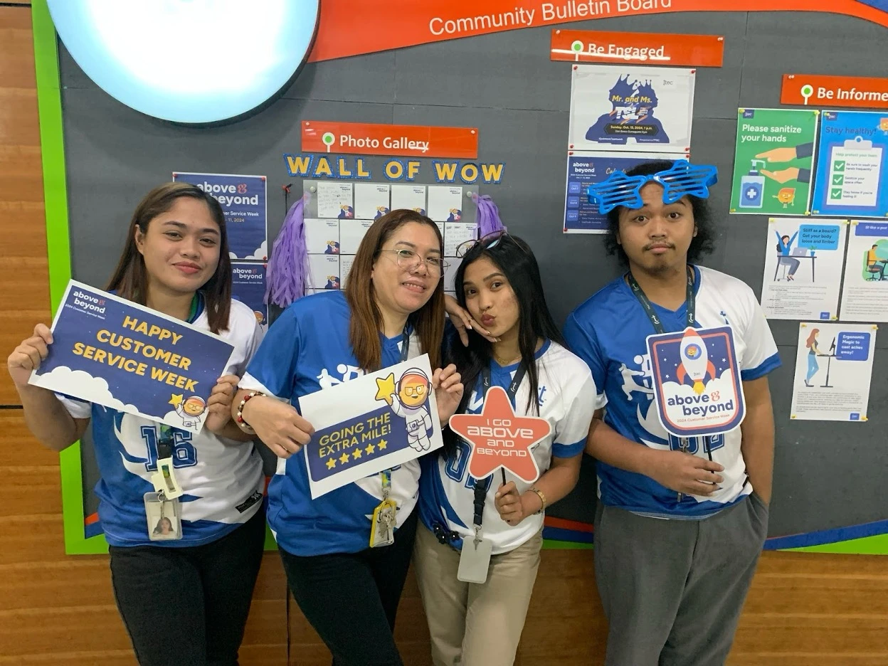 Four TTEC employees holding customer service week signs.
