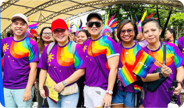 Group of people wearing pride shirts and holding flags
