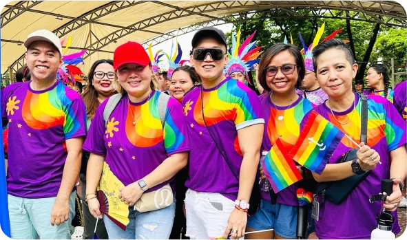 Group of people wearing pride shirts and holding flags