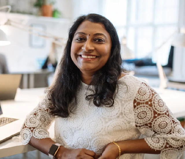 Woman at her desk smiling at the camera