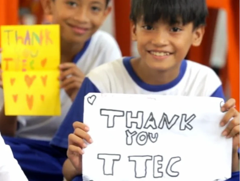 A student holding a sign that says "Thank you TTEC"