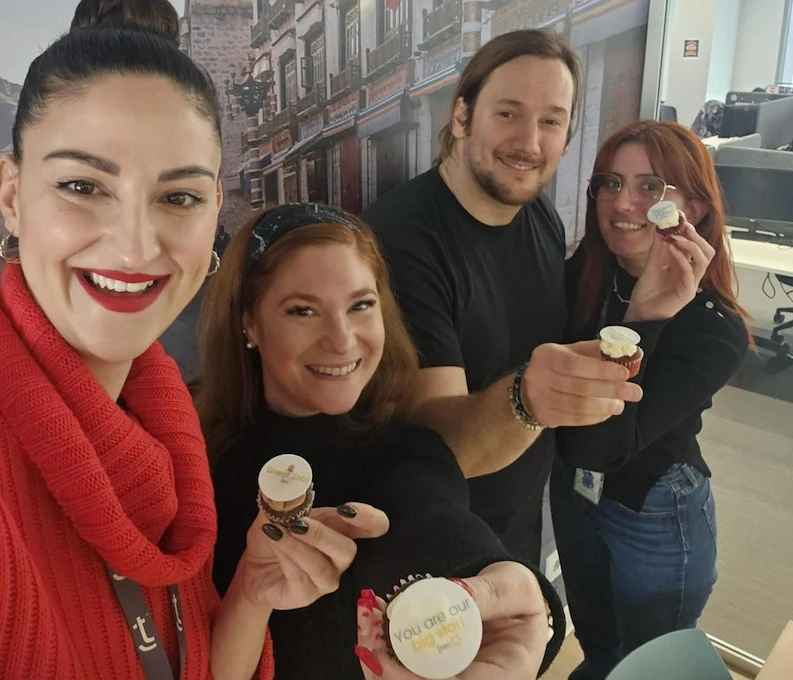 Four TTEC Athens employees taking a photo while holding cupcakes.