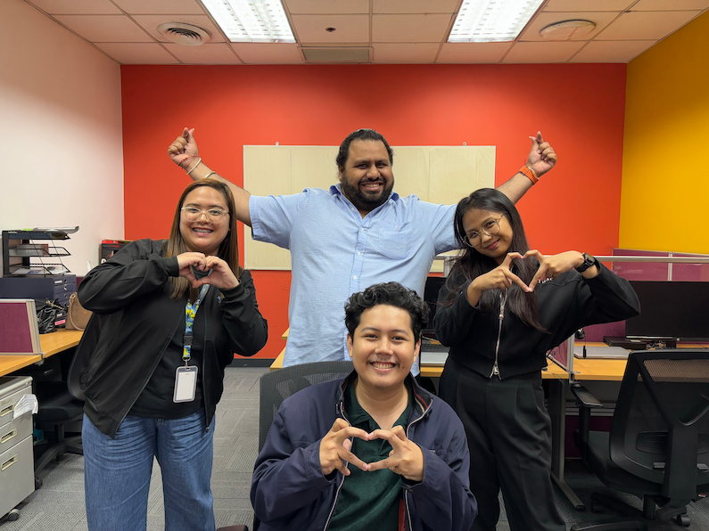 A team of four TTEC employees happily posing for a picture in the office.
