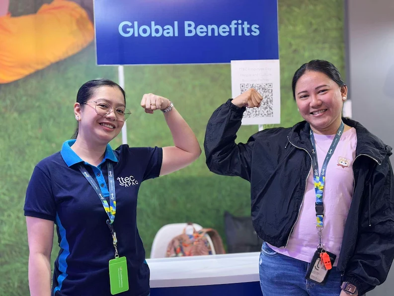 Two TTEC employees posing for a photo in front of a job fair booth.