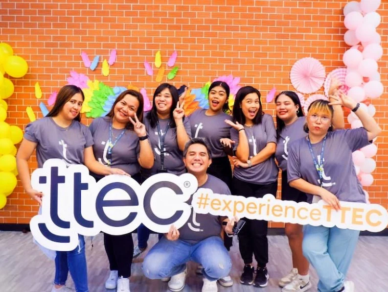 TTEC Philippines employees posing for a picture, holding fun signs.